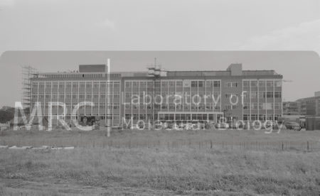 Construction of the 13-bay extension to the LMB building: external view looking across fields and car parks to the nearly completed building, showing the loading bay, stores entrance, and the extended workshop.