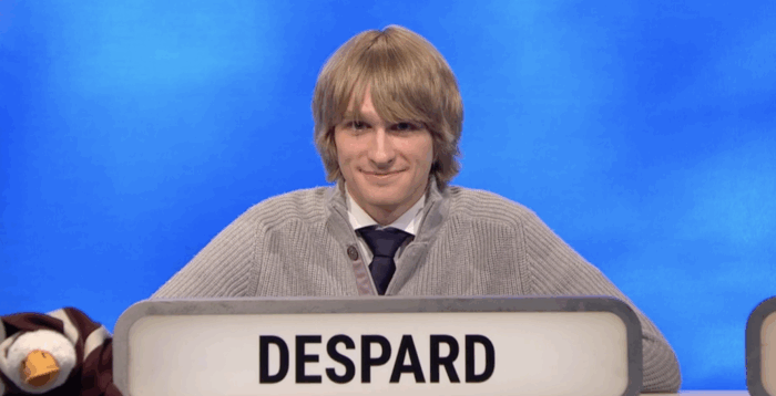 Oscar Despard sits behind a lit sign reading his surname in capital letters. To his right is a stuffed goose, the team’s mascot.