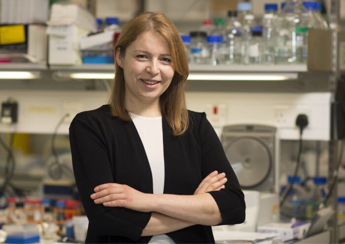 Patrycja Kozik with arms crossed, smiling, stood in a laboratory